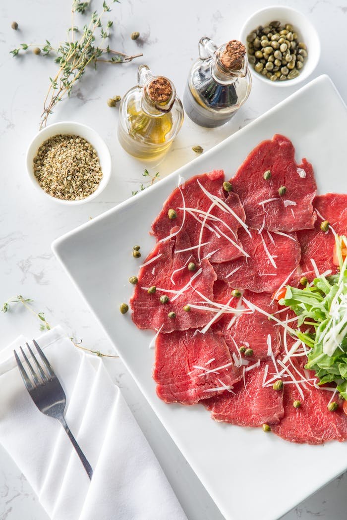 Crafting Captivating Headlines: Your awesome post title goes here Delicious beef carpaccio with capers, olive oil, and fresh toppings on a white plate.