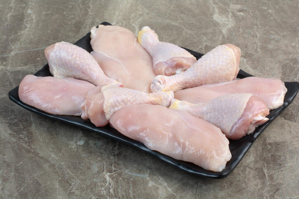 fresh unprepared chicken legs dark plate